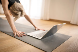 Woman 40+ practices yoga at home with notebook. Online yoga class. Woman 40+ practices yoga at home with notebook. Online yoga class.